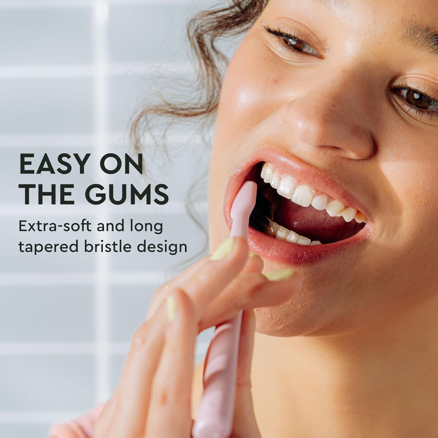 Woman smiling as she brushes with the Classic Toothbrush 4-Pack, featuring gentle bristle design.