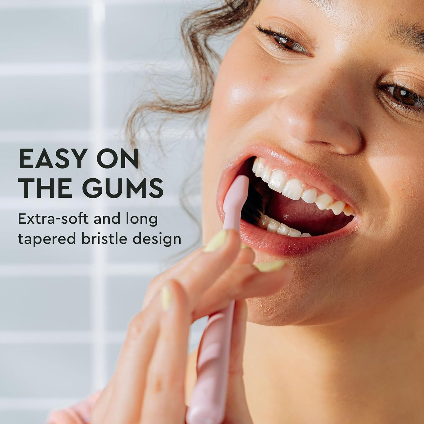 Woman smiling as she brushes with the Classic Toothbrush 4-Pack, featuring gentle bristle design.