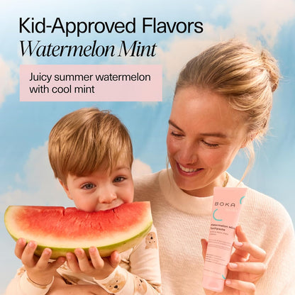 A woman smiles holding Watermelon Mint n-Ha Toothpaste as a child enjoys watermelon under a blue sky.