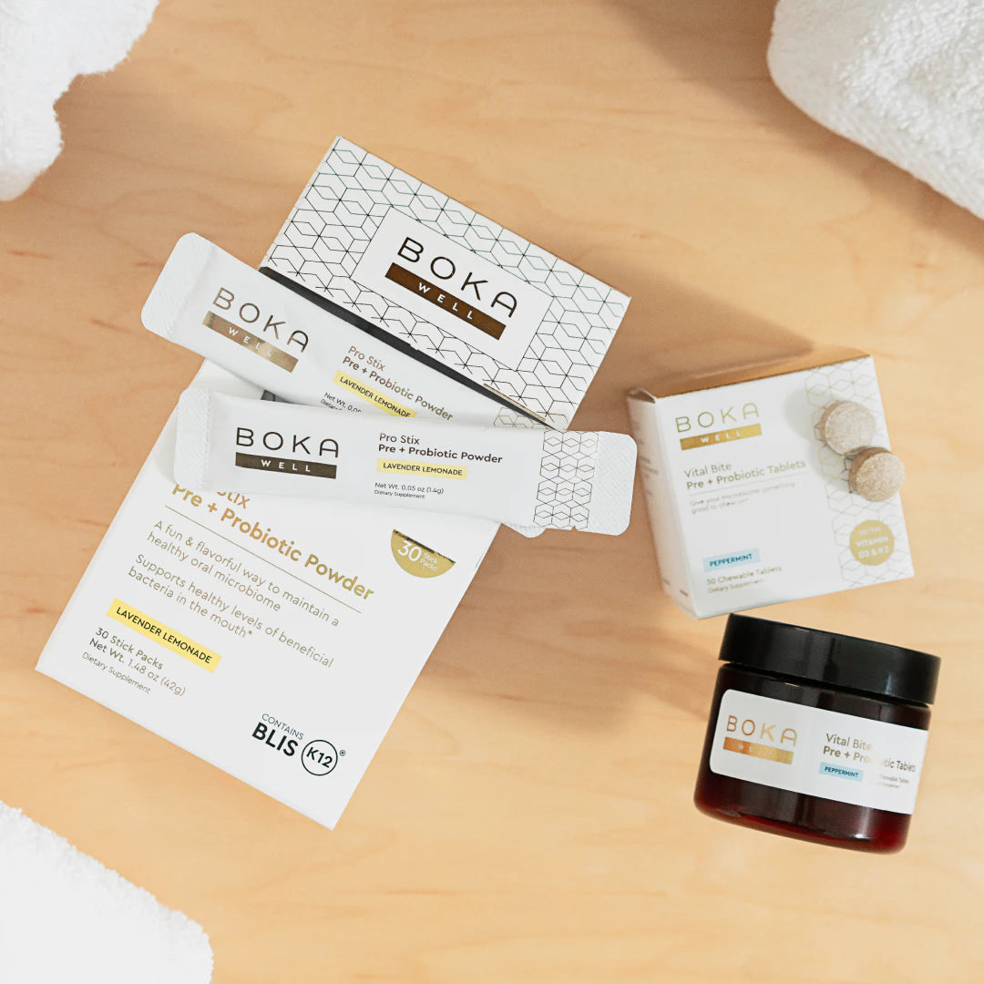 Boka oral probiotic products, including powder sticks, tablets, and a jar, on a wooden surface.
