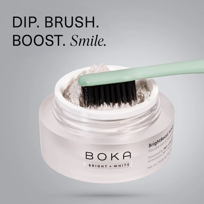 A toothbrush dips into BrightBoost Whitening Powder with text: DIP. BRUSH. BOOST. Smile.