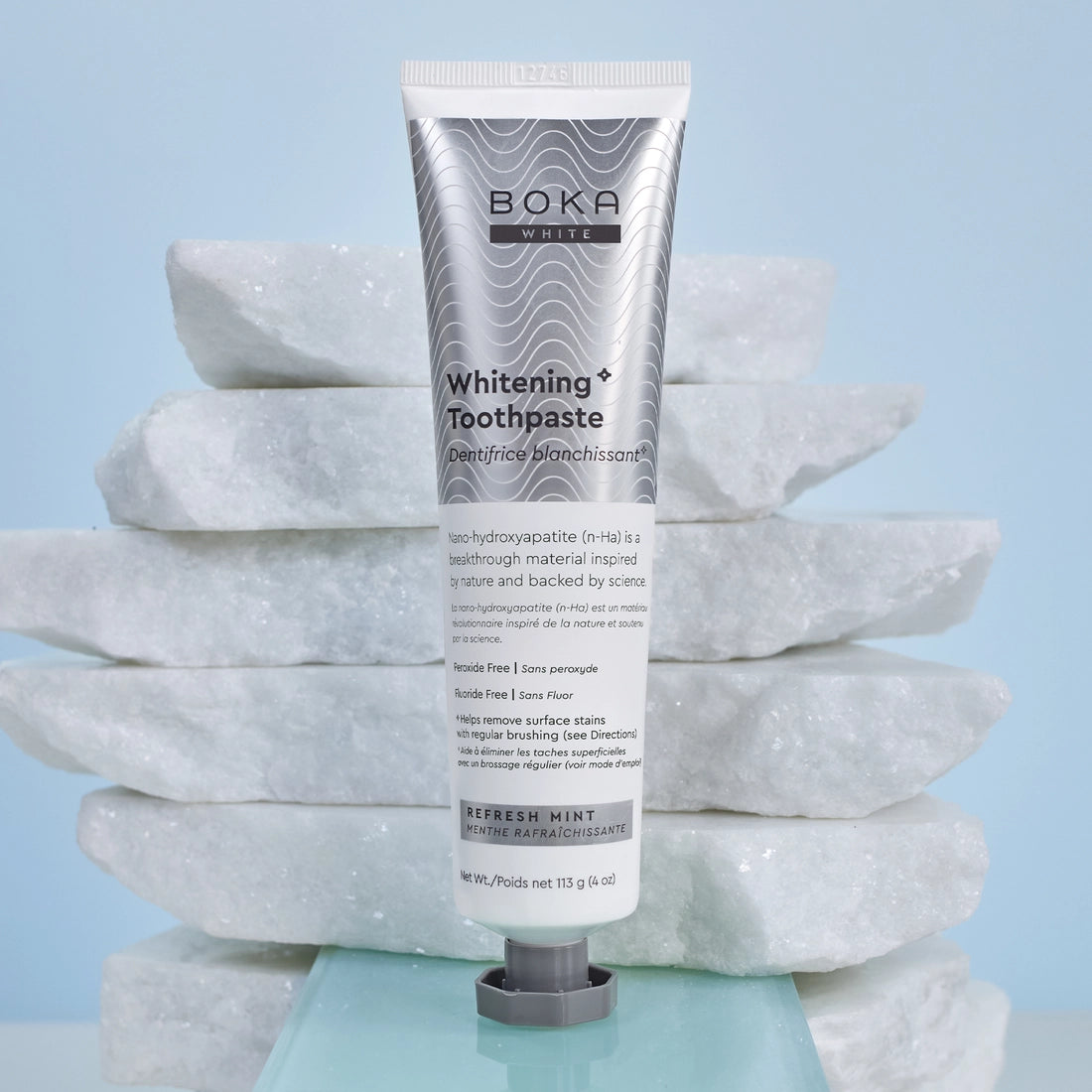 A tube of Refresh Mint Whitening* n-Ha Toothpaste stands upright on stacked white marble slabs.