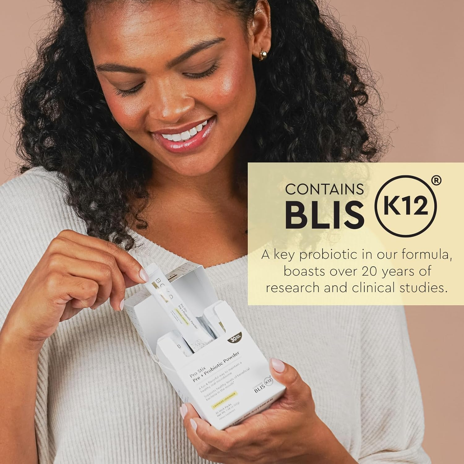 Smiling woman holds Pro Stix Pre + Probiotic Powder, highlighting oral probiotic benefits beside her.