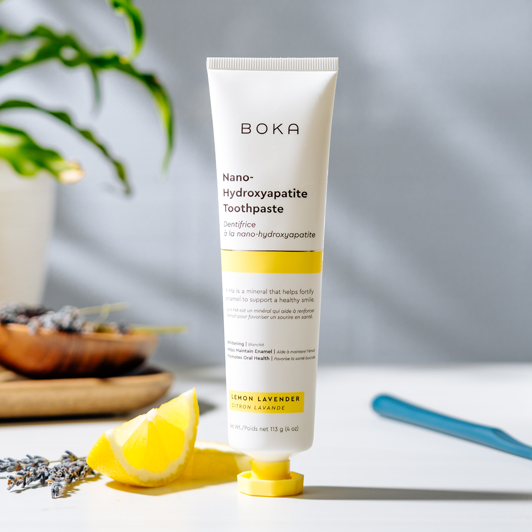 A tube of Boka Nano-Hydroxyapatite Toothpaste stands upright beside a lemon wedge and lavender.