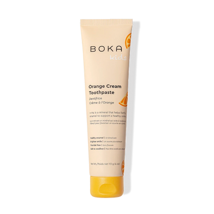 Orange Cream n-Ha Toothpaste for kids with nano-hydroxyapatite and orange slices on black background.