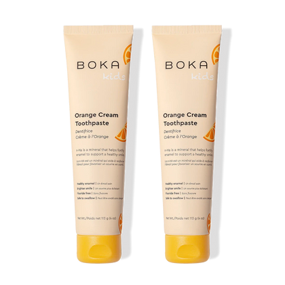 Two tubes of Orange Cream n-Ha Toothpaste stand side by side to help remineralize teeth.